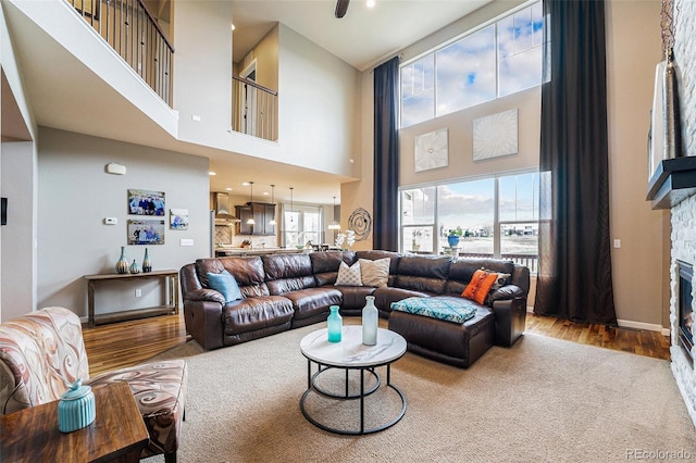 2349 Hickory Pl, Erie, CO 80516 - living area featuring carpet flooring, a high ceiling, a fireplace, baseboards, and wood finished floors