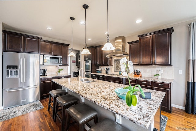 2349 Hickory Pl, Erie, CO 80516 - kitchen with wall chimney range hood, stainless steel appliances, wood finished floors, and dark brown cabinets