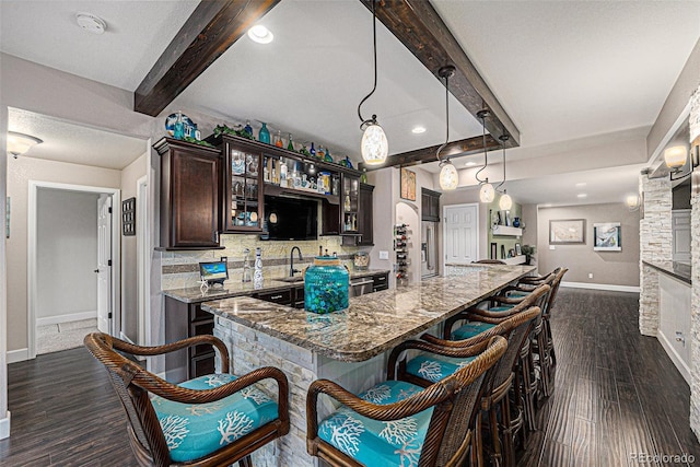 2349 Hickory Pl, Erie, CO 80516 - kitchen featuring dark brown cabinetry, beam ceiling, glass insert cabinets, baseboards, and a kitchen bar