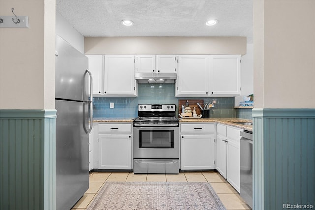 8773 W Cornell Ave Unit 10, Lakewood, CO 80227 - kitchen with stainless steel appliances, under cabinet range hood, white cabinetry, a wainscoted wall, and a textured ceiling