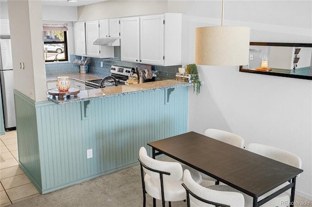 8773 W Cornell Ave Unit 10, Lakewood, CO 80227 - kitchen with stainless steel appliances, tasteful backsplash, under cabinet range hood, and a breakfast bar area