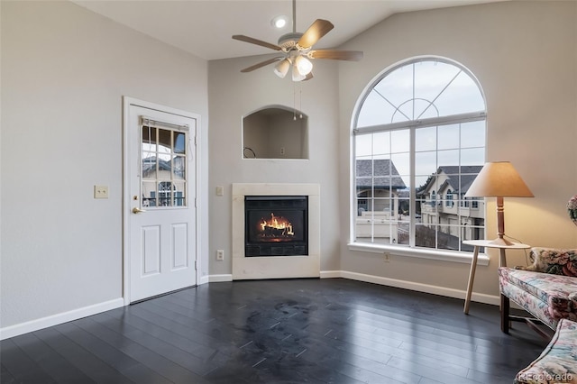 unfurnished living room with a warm lit fireplace, dark wood-style flooring, a healthy amount of sunlight, and baseboards