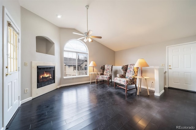 sitting room featuring vaulted ceiling, a lit fireplace, dark wood-style floors, and baseboards