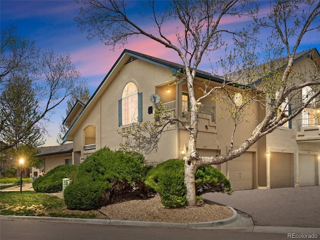 view of front facade with a balcony, stucco siding, and a garage