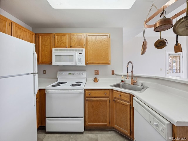 kitchen with white appliances, a sink, light countertops, light tile patterned floors, and brown cabinetry
