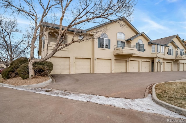 8621 E Dry Creek Rd Unit 325, Englewood, CO 80112 - townhome / multi-family property with driveway, an attached garage, stucco siding, and a balcony