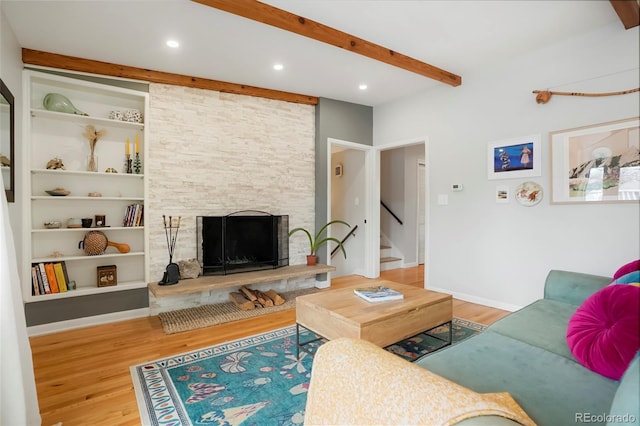 living room with beamed ceiling, wood finished floors, stairs, built in shelves, and a fireplace