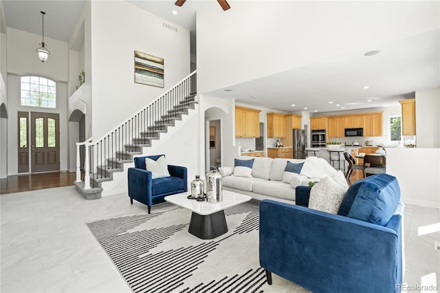 1511 Peninsula Cir, Castle Rock, CO 80104 - living room featuring a towering ceiling, arched walkways, stairway, healthy amount of natural light, and recessed lighting