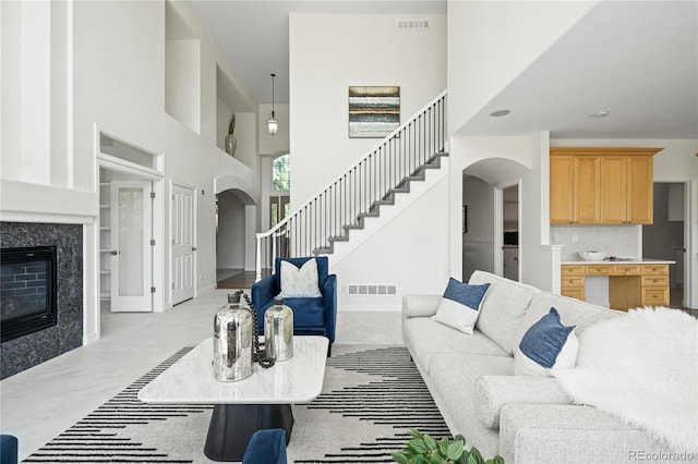 1511 Peninsula Cir, Castle Rock, CO 80104 - living room featuring arched walkways, a towering ceiling, stairway, built in shelves, and a premium fireplace