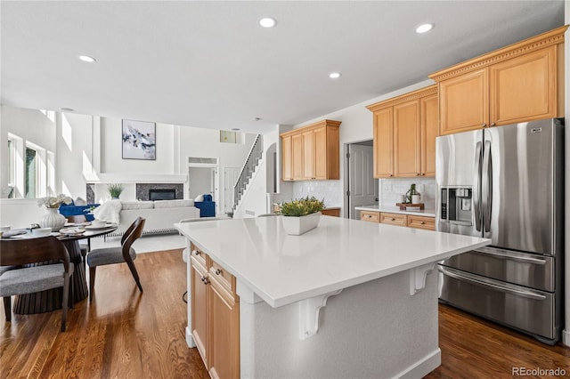 1511 Peninsula Cir, Castle Rock, CO 80104 - kitchen featuring stainless steel fridge, a center island, dark wood-style flooring, a glass covered fireplace, and light countertops