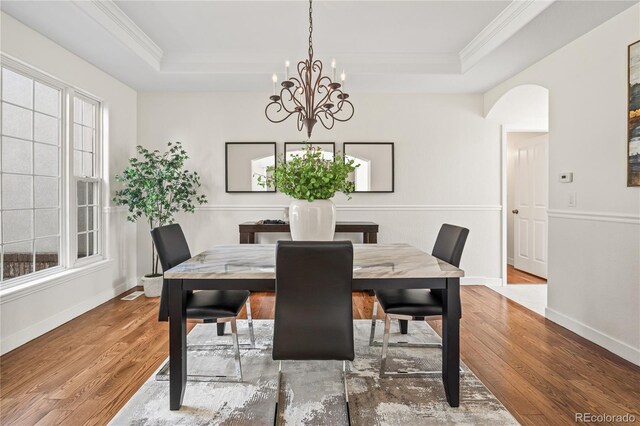 1511 Peninsula Cir, Castle Rock, CO 80104 - dining area featuring a raised ceiling, crown molding, wood finished floors, arched walkways, and a chandelier