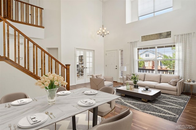 interior space with hardwood / wood-style floors, a towering ceiling, an inviting chandelier, and french doors