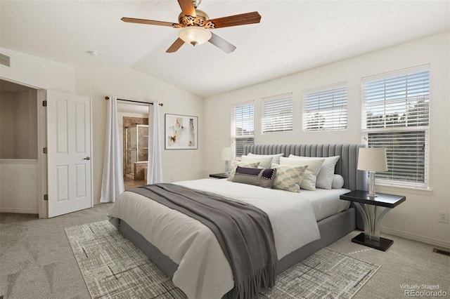 carpeted bedroom with ensuite bath, ceiling fan, and vaulted ceiling