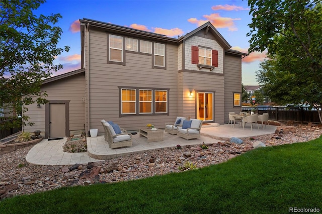 back house at dusk featuring outdoor lounge area, a yard, and a patio