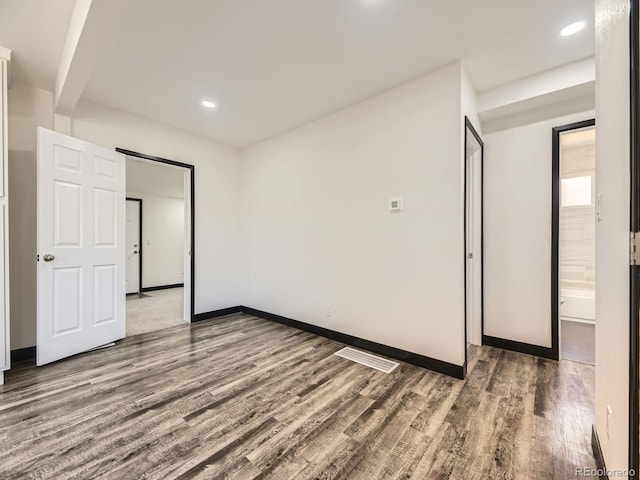 empty room with wood finished floors, baseboards, and recessed lighting