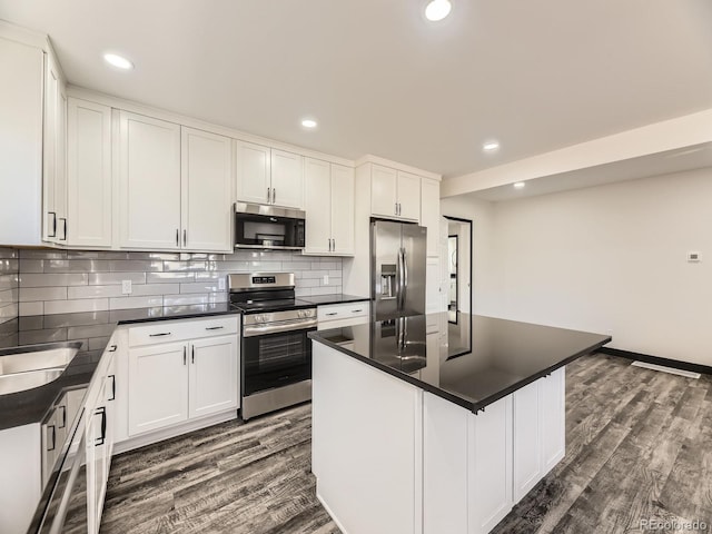 kitchen featuring stainless steel appliances, dark wood-style flooring, dark countertops, decorative backsplash, and white cabinets