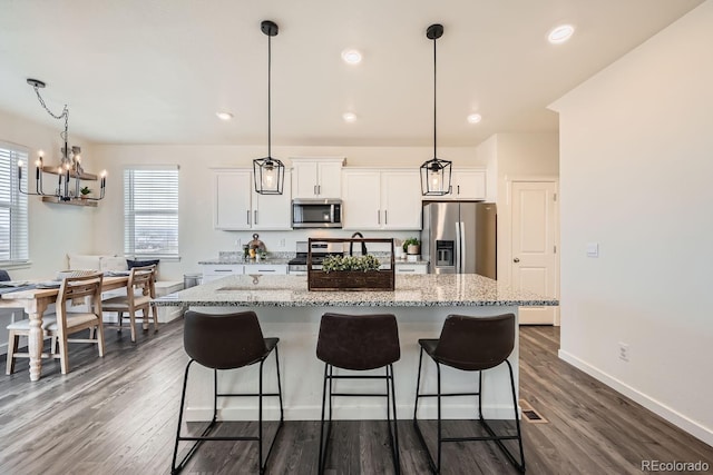 kitchen with appliances with stainless steel finishes, a center island, hanging light fixtures, and white cabinets