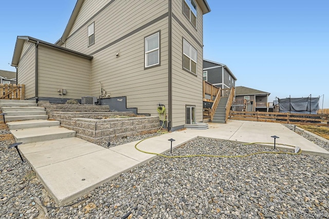 back of property featuring cooling unit, a trampoline, and a patio area