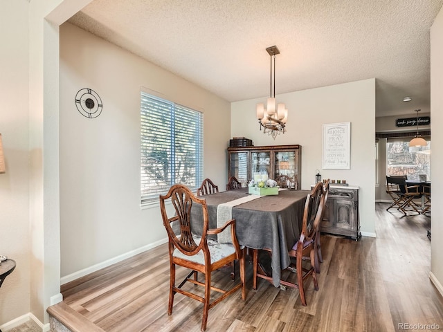 dining room featuring a textured ceiling, hardwood / wood-style floors, plenty of natural light, and a notable chandelier