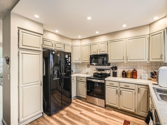 kitchen featuring black appliances, sink, light hardwood / wood-style flooring, and tasteful backsplash