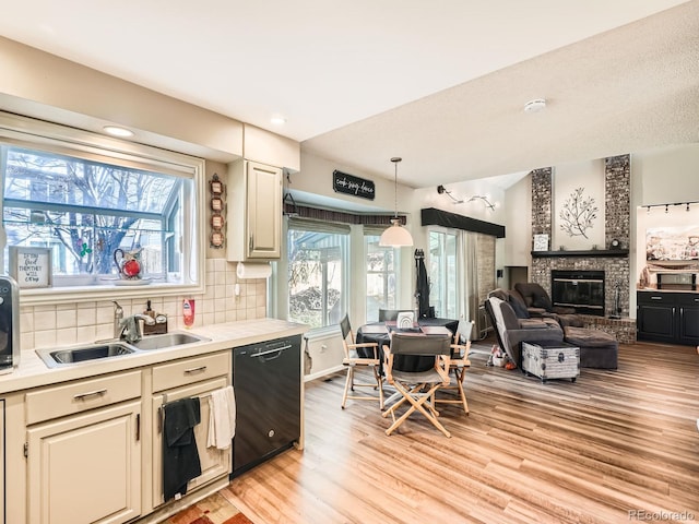 kitchen with dishwasher, sink, decorative light fixtures, decorative backsplash, and a fireplace