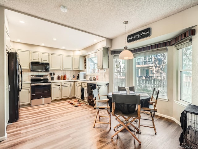 kitchen featuring black appliances, decorative light fixtures, backsplash, and light hardwood / wood-style flooring