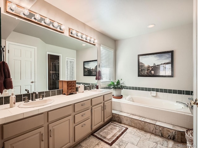 bathroom with vanity and a relaxing tiled tub