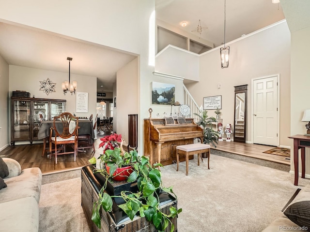 living room with hardwood / wood-style floors, a towering ceiling, and an inviting chandelier