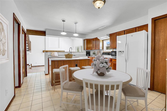 13270 W 65th Ave, Arvada, CO 80004 - kitchen featuring white refrigerator with ice dispenser, brown cabinets, light countertops, decorative light fixtures, and light tile patterned flooring