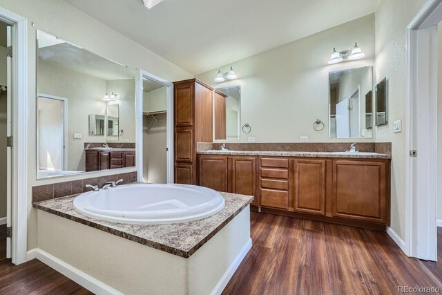 bathroom with hardwood / wood-style flooring, vanity, and a bath