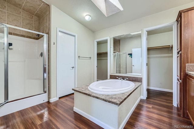 bathroom featuring walk in shower, a skylight, sink, and hardwood / wood-style floors