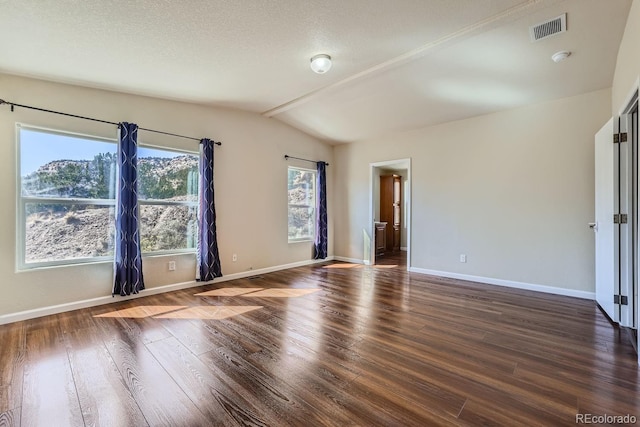 spare room with vaulted ceiling, dark hardwood / wood-style floors, and a textured ceiling