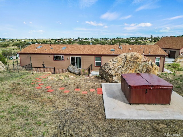 rear view of property featuring a hot tub and a patio area