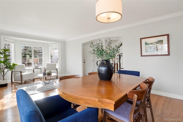 dining area with crown molding, baseboards, and light wood-type flooring