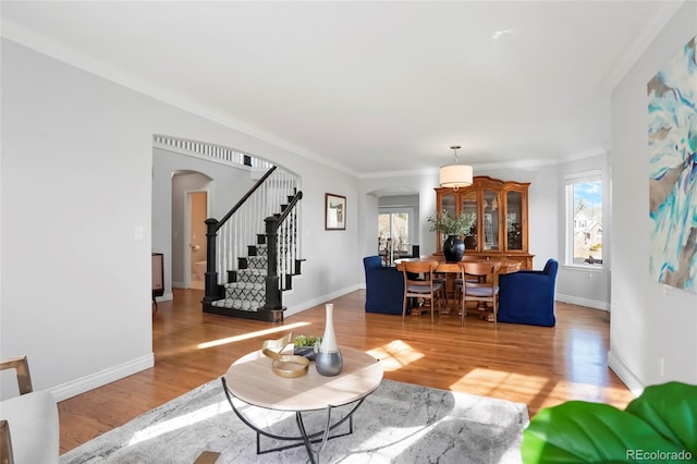 living room featuring stairway, arched walkways, wood finished floors, and crown molding