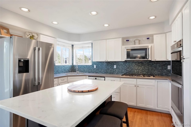 kitchen featuring backsplash, light wood-style flooring, stainless steel appliances, and a sink