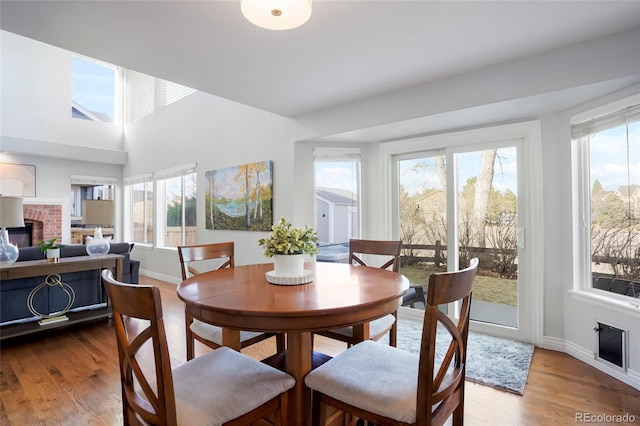 dining space featuring wood finished floors, plenty of natural light, a fireplace, and baseboards