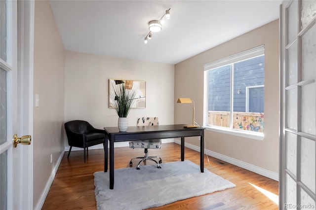 office area featuring visible vents, baseboards, and wood finished floors