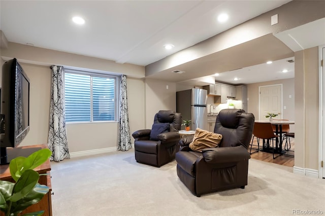 living area featuring recessed lighting, baseboards, and light carpet