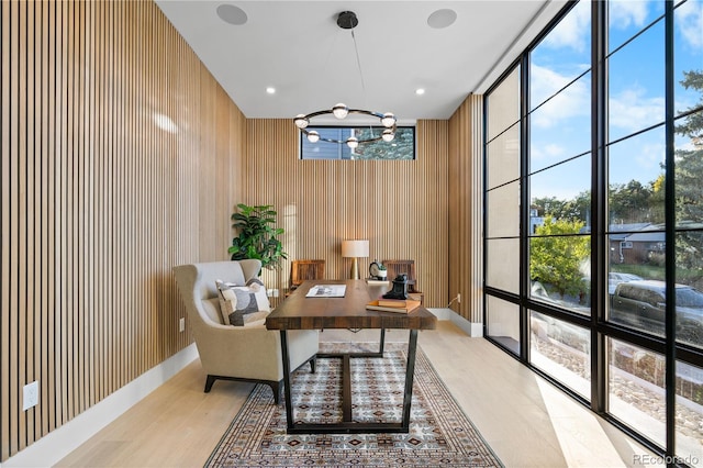 office with light wood-type flooring, an inviting chandelier, a wall of windows, and plenty of natural light