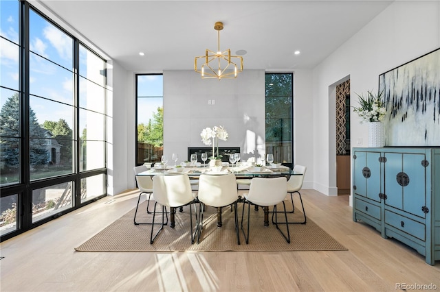 dining area with a notable chandelier, light hardwood / wood-style flooring, and floor to ceiling windows