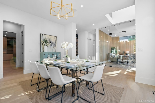 dining room featuring a notable chandelier, a skylight, and light hardwood / wood-style floors