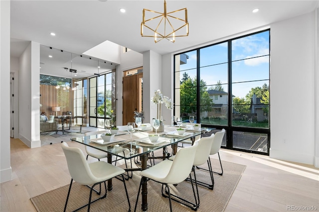 dining room featuring light wood-type flooring, floor to ceiling windows, and a chandelier