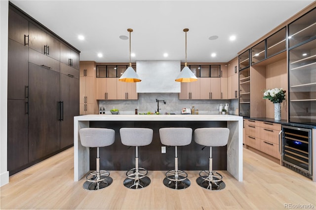 kitchen featuring pendant lighting, light hardwood / wood-style flooring, wine cooler, and tasteful backsplash