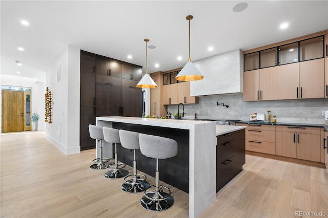 kitchen featuring pendant lighting, light wood-type flooring, decorative backsplash, and a kitchen island