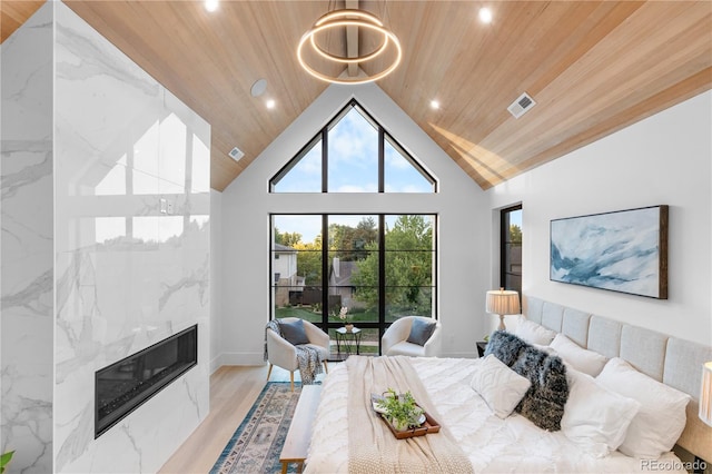 bedroom with light hardwood / wood-style floors, wood ceiling, high vaulted ceiling, a high end fireplace, and a notable chandelier