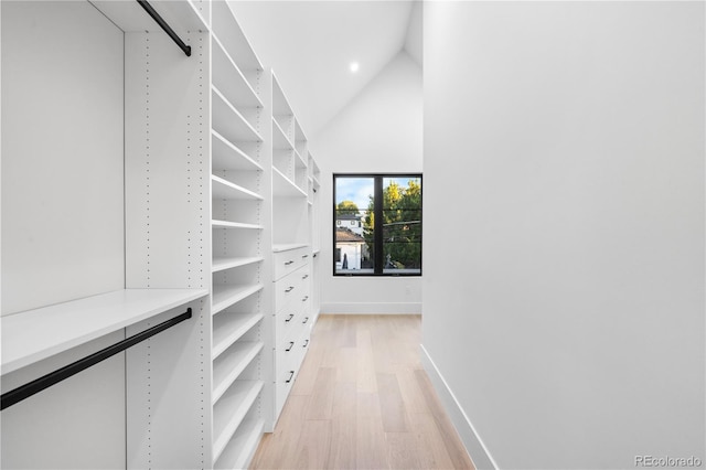 walk in closet featuring high vaulted ceiling and light hardwood / wood-style floors