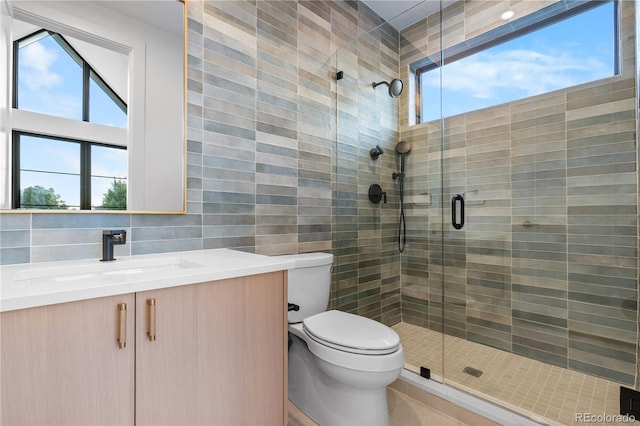 bathroom with tile walls, decorative backsplash, a shower with door, vanity, and toilet