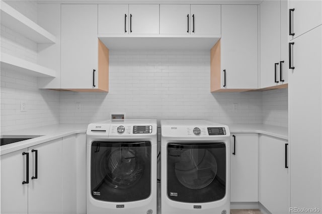 washroom with cabinets and washing machine and clothes dryer