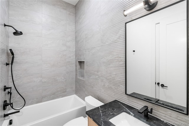 full bathroom featuring tiled shower / bath, vanity, and toilet